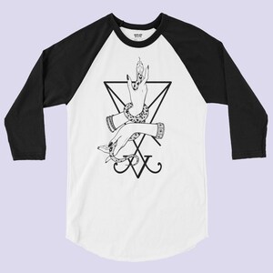 K&ouml;nnte beinhalten: Ein wei&szlig;-schwarzes Baseball-T-Shirt mit einer schwarz-wei&szlig;en Illustration einer Hand, die eine Schlange, ein Pentagramm und den Text "XV" h&auml;lt.