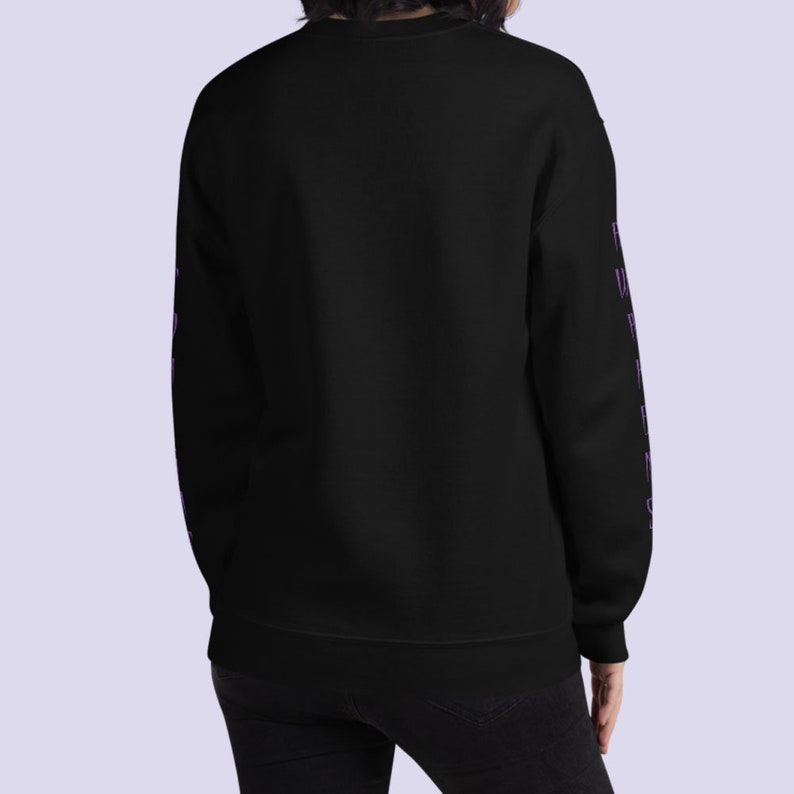 May include: Black sweatshirt with long sleeves and purple text on the sleeves. The text is hard to read but appears to be "Friends"