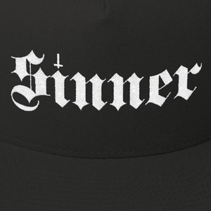 Puede incluir: Gorra de b&eacute;isbol negra con un dise&ntilde;o bordado en blanco que dice "Sinner" con una cruz sobre la primera letra.