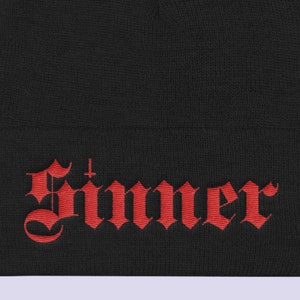 May include: Black beanie with a red embroidered word "Sinner" in a gothic font.
