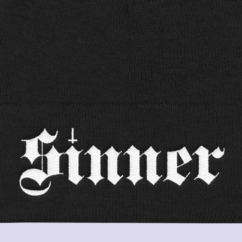 May include: Black beanie with a white embroidered "Sinner" logo in a gothic font.