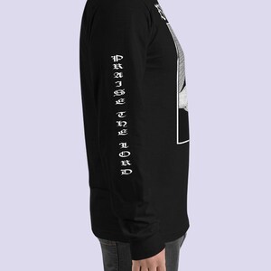 May include: Black long-sleeve shirt with a white graphic print of a hand holding a knife. The text "PRAISE THE LORD" is printed vertically on the left sleeve.