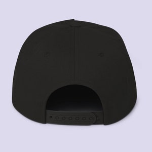 Puede incluir: Gorra de b&eacute;isbol negra, sin estructura, de visera plana, con una correa ajustable negra en la parte posterior.