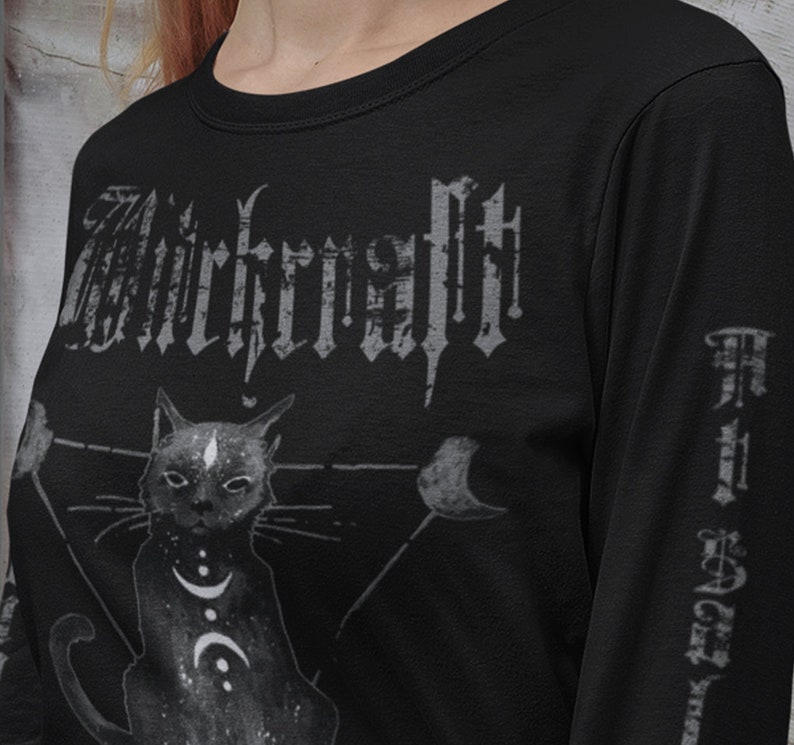 Pode incluir: Camiseta preta de manga comprida com uma estampa gr&aacute;fica de um gato preto com uma lua crescente e estrelas. O texto "Witchcraft" &eacute; impresso em uma fonte g&oacute;tica na parte frontal da camiseta.