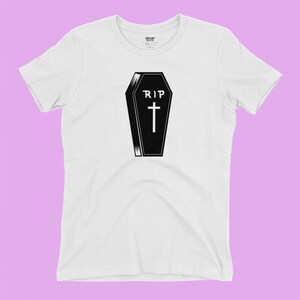 K&ouml;nnte beinhalten: Wei&szlig;es T-Shirt mit einer schwarz-wei&szlig;en Illustration eines Sarges mit dem Text "RIP" und einem Kreuz.