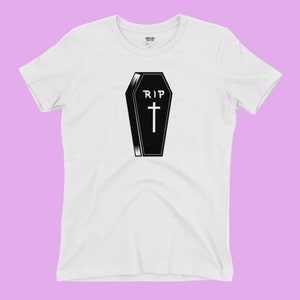 K&ouml;nnte beinhalten: Wei&szlig;es T-Shirt mit einer schwarz-wei&szlig;en Illustration eines Sarges mit dem Text "RIP" und einem Kreuz.