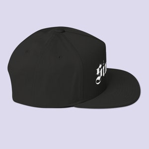 Puede incluir: Gorra de b&eacute;isbol negra ajustada con el texto 'Gothic' bordado en blanco.