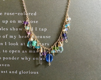 Puede incluir: Un delicado collar de oro con una cascada de piedras preciosas de colores, incluyendo cristales azules, verdes, morados y transparentes. El collar presenta una variedad de formas y tamaños de cuentas, ensartadas en una fina cadena de oro.