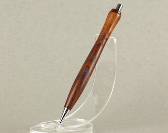 May include: A wooden pen with a brown and dark brown wood grain pattern. The pen is sitting in a clear plastic stand.