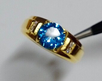 May include: A gold ring with a blue gemstone and small clear gemstones on the band.