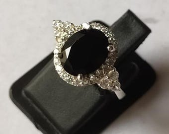 May include: A silver ring with a large black oval gemstone surrounded by a halo of smaller white gemstones.
