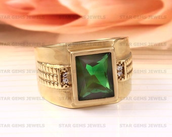May include: A gold ring with a large, emerald green gemstone and two smaller, clear gemstones on the band.