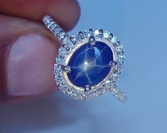 May include: A silver ring with a large blue star sapphire surrounded by a halo of smaller diamonds.