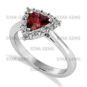 May include: A silver ring with a triangular, deep red gemstone and a halo of smaller, clear stones. The ring has a smooth, polished band, with the text "STAR GEMS" repeated around the ring.