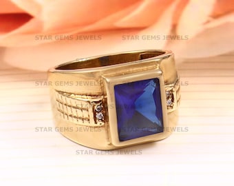 May include: A gold ring with a large blue square-shaped gemstone and two smaller white gemstones on the band.