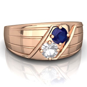 May include: A rose gold band ring with a blue sapphire and a white diamond. The ring has a grooved design.