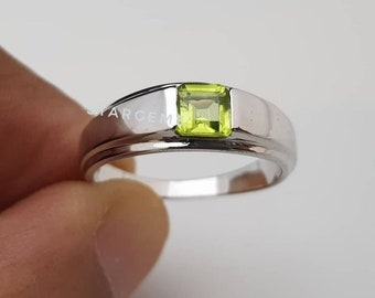 May include: A silver ring with a square green gemstone set in the center.