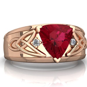 Pode incluir: Um anel de ouro rosa com uma grande gema de rubi triangular e dois pequenos diamantes. O anel apresenta um design de nó celta.