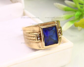 May include: A gold ring with a large, square, blue gemstone and two smaller, round, white gemstones on the band.