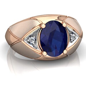 Könnte beinhalten: Ein Ring aus Roségold mit einem großen ovalen blauen Saphir und zwei kleineren runden weißen Diamanten an jeder Seite.