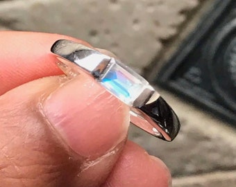 May include: A silver ring with a rectangular iridescent gemstone.