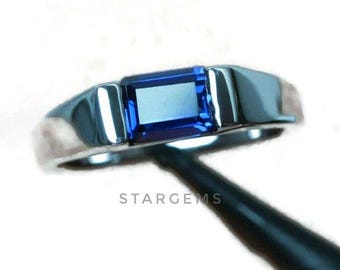 May include: A silver ring with a blue rectangular gemstone. The ring is set in a simple, modern style.