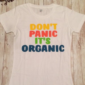 Może przedstawiać: Biała koszulka z napisem "Don't Panic It's Organic" w kolorach tęczy.