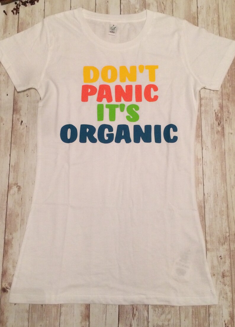 Może przedstawiać: Biała koszulka z napisem "Don't Panic It's Organic" w kolorach tęczy.