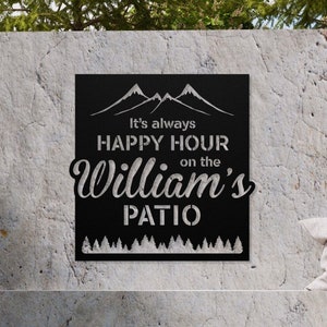 May include: Black metal sign with a mountain silhouette and the text "It's always happy hour on the William's patio".