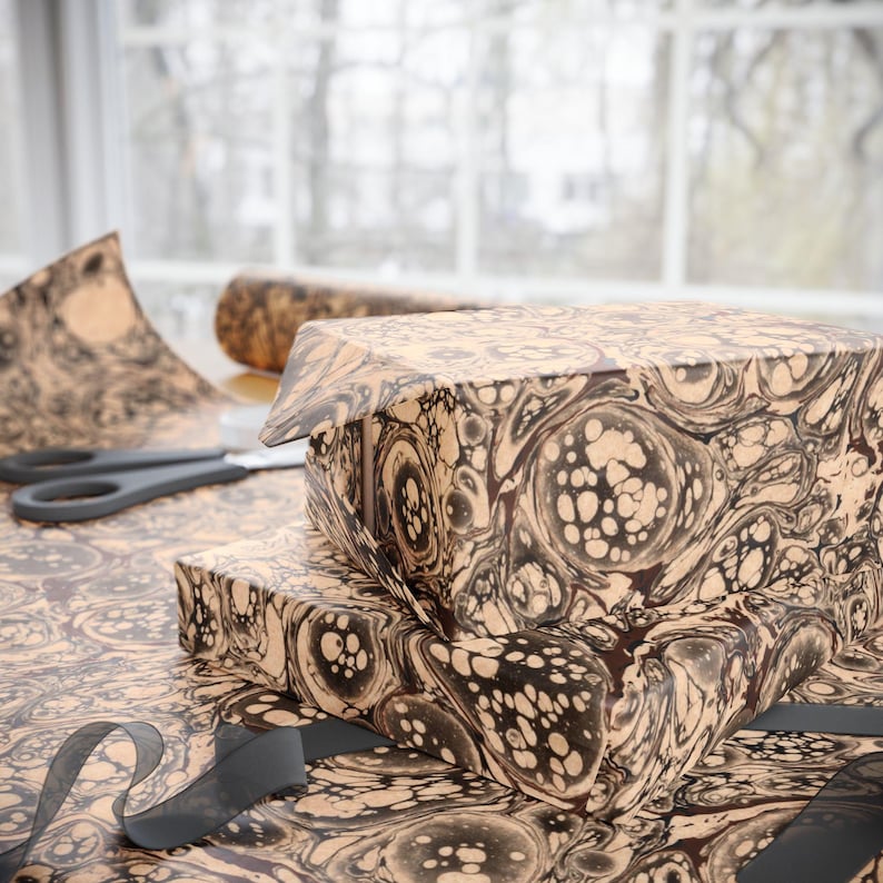 May include: Two boxes wrapped in brown and black marbled paper with a black ribbon. The paper has a swirling pattern with white and brown accents.