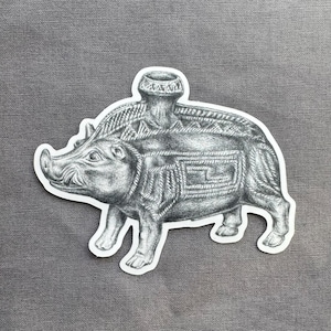 May include: A black and white sticker featuring a detailed pencil drawing of a boar with an ornate design on its back. The boar has a decorative vessel on its back. The sticker is on a gray background.