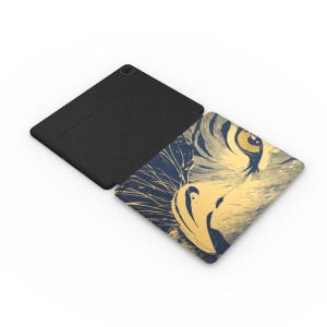 May include: A black case for an iPad or tablet with a close-up of a tiger's face on the front. The tiger's eye is a bright yellow and the fur is a light brown and blue.