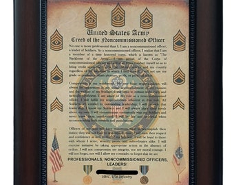 May include: A framed print of the United States Army Creed of the Noncommissioned Officer. The print features a brown background with gold text and images of military insignia. The text includes the words "United States Army" and "Creed of the Noncommissioned Officer".