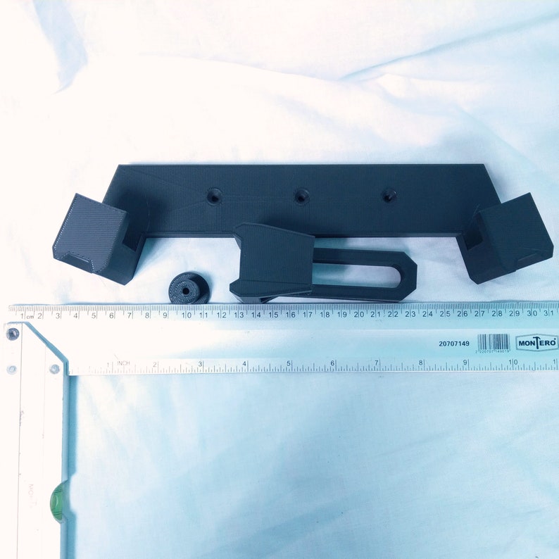 May include: A 3D printed black plastic bracket with three holes and a small round knob. The bracket is designed to be mounted to a wall or other surface.