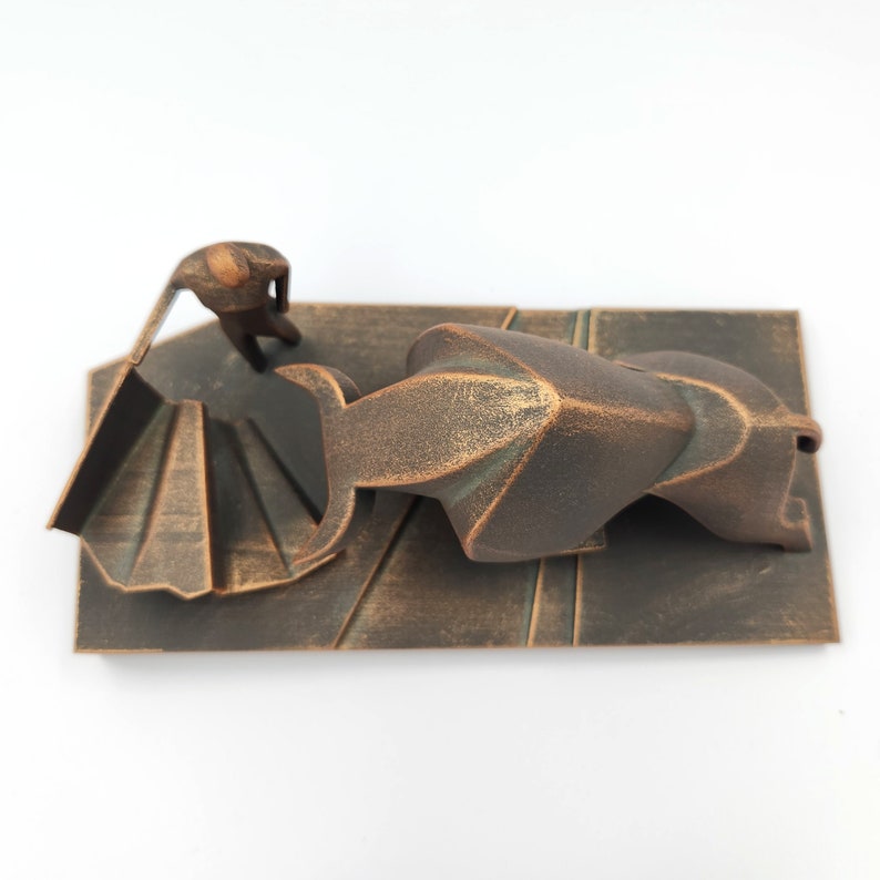 May include: A bronze sculpture of a person standing on a staircase, looking down at a large, abstract bronze form.