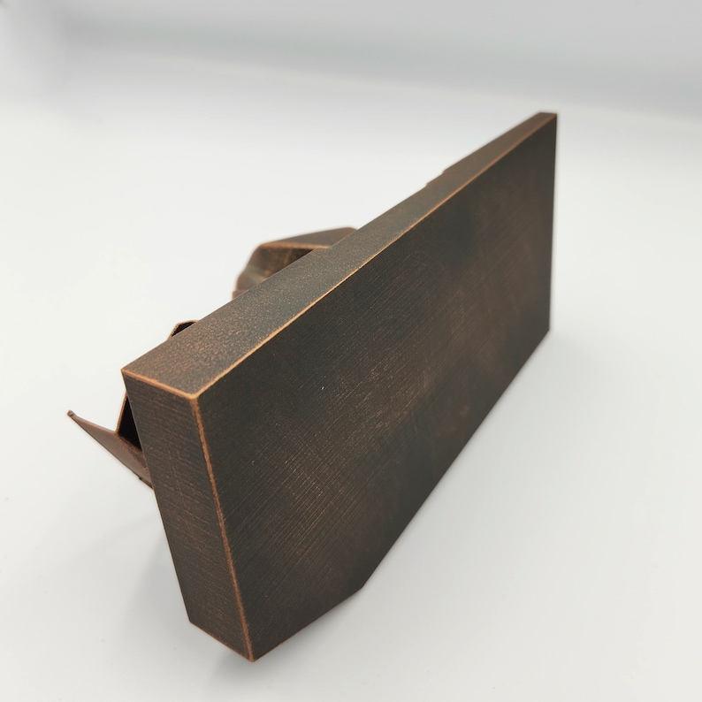 May include: A dark brown metal sculpture of a building with a textured surface. The sculpture is on a white background.