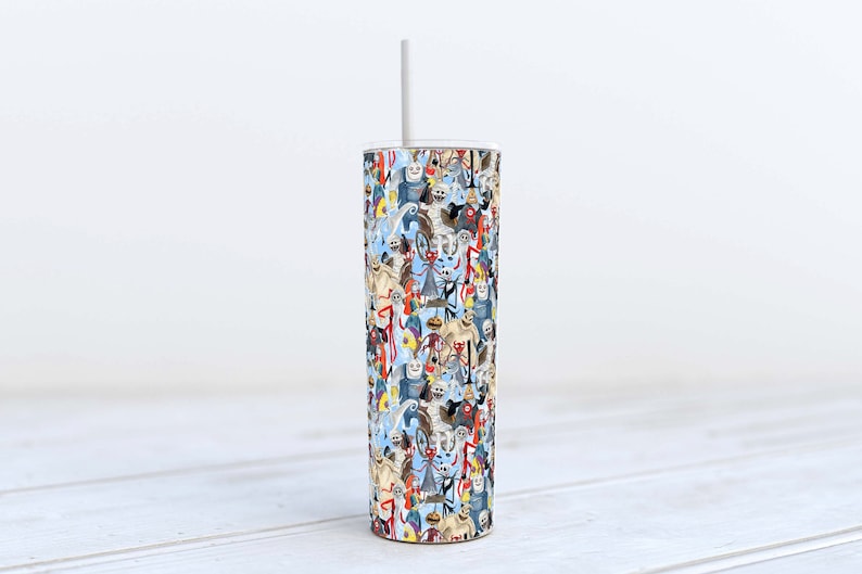 May include: A stainless steel tumbler with a white straw. The tumbler is covered in a colorful pattern of cartoon characters.