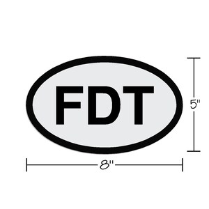 May include: A white oval sticker with a black outline and the text "FDT" in black letters. The sticker is 8 inches wide and 5 inches tall.