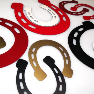 May include: A set of eight horseshoe-shaped metal wall decor pieces in various colours, including red, black, gold, and white.