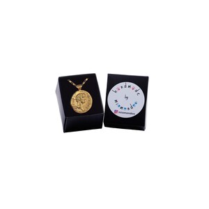 May include: Gold necklace with a round pendant featuring a profile of a woman's face. The necklace is in a black box with a white label that says "handmade by mimomondoo".