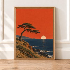 May include: A framed art print featuring a coastal landscape with a lone pine tree on a grassy cliff overlooking a deep blue ocean. A large, pale sun sits on the horizon against a vibrant, solid orange sky, casting a reflection on the water.