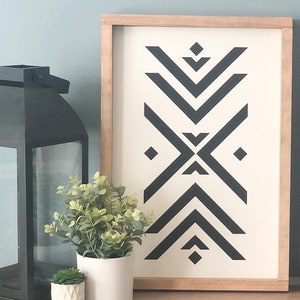 May include: A framed black and white geometric design print with a wood frame. The print features a repeating pattern of black triangles and diamonds on a white background.