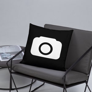 May include: A black throw pillow with a white camera icon in the center.