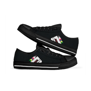 Może przedstawiać: Czarne płócienne buty sportowe o niskim profilu z białą paską i kolorowym wzorem graficznym po bokach. Grafika przedstawia stylizowane pasmo górskie z napisem "TOGO!" po bokach.