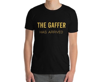 May include: A black t-shirt with the text "THE GAFFER HAS ARRIVED" in gold lettering.