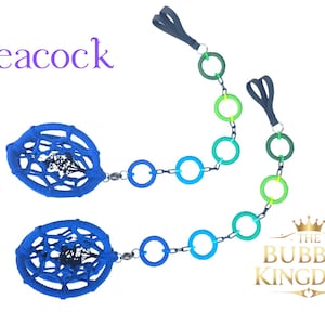 Può includere: Due copricapezzoli blu a forma di acchiappasogni con una catena di anelli blu e verdi. Il testo "Peacock" è in viola. Il logo The Bubble Kingdom si trova in basso a destra.