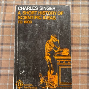 May include: A black and orange book cover with the title "A Short History of Scientific Ideas to 1900" by Charles Singer. The cover features an illustration of a skeleton writing on a scroll.