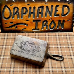 May include: A cast iron skillet with a diamond-shaped logo that reads "Highest Quality Cast Iron No. Littletown Home & Furry Co. New York - Made in U.S.A."