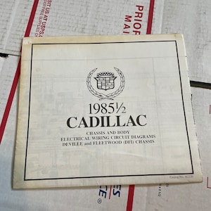 May include: A vintage Cadillac service manual for the 1985 1/2 models. The cover features the Cadillac emblem, the model year, and the text "Chassis and Body Electrical Wiring Circuit Diagrams." The manual is on a white background.