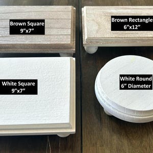 May include: Four wooden display stands in various shapes and colors. Includes a brown square (9"x7"), a white square (9"x7"), a brown rectangle (6"x12"), and a white round stand (6" diameter). Each stand has small, round feet.